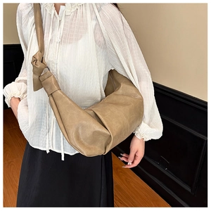 Detail of soft khaki pleated crescent bag with unique knot shoulder strap decoration