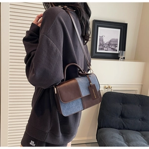Model wearing a brown leather and blue denim patchwork crossbody bag with a fashion tag