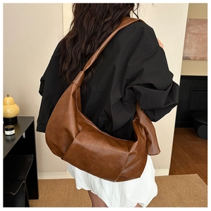 Detail of a large brown retro pleated PU leather hobo bag with stitched seams