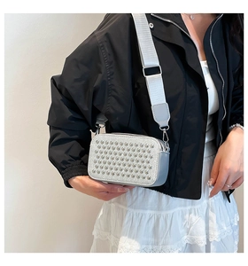 Detail of silver studded crossbody bag with metallic finish and adjustable wide strap