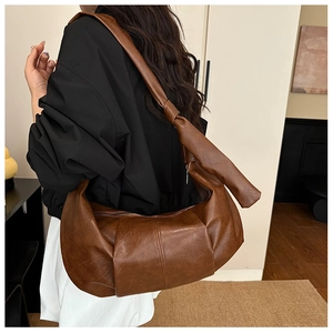 Detail of large brown hobo bag featuring retro leather texture and knot shoulder strap