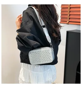 Silver studded crossbody camera bag with wide shoulder strap shown on a model