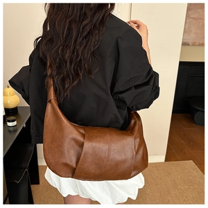 Detailed back view of a large brown pleated hobo bag worn by a model in a casual setting