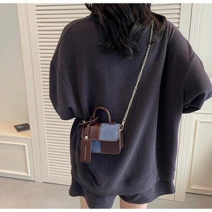 Detail of brown leather and blue denim mini bag with gold chain and fashion tag