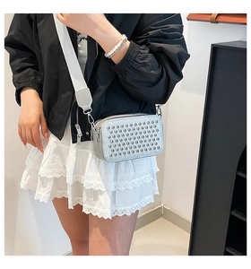 Detail of silver studded crossbody camera bag with adjustable wide fabric strap on a model
