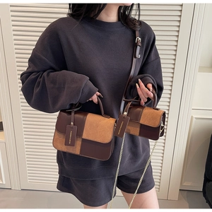 Detail of vintage brown shoulder bag with mini pouch and elegant chain strap on model