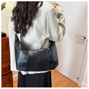Detailed view of black retro soft leather dumpling bag worn on shoulder in a cozy room