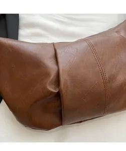 Detail of soft brown leather bag showing premium texture and vertical decorative stitching