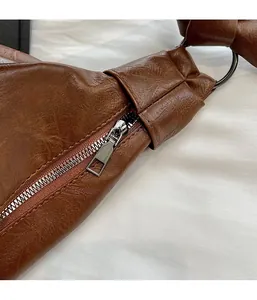 Close-up of smooth silver metal zipper and ring buckle on brown leather bag