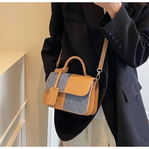 Detail of contrast stitch handbag featuring ginger leather and grey denim patchwork