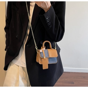 Chic brown leather and blue denim patchwork mini bag with golden chain strap on model