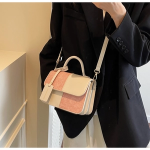 Detail of pink and white patchwork handbag with handle, worn by model in suit