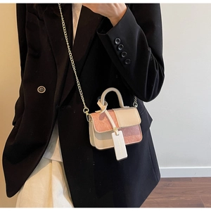 Detail of a mini pink and white crossbody bag with glitter finish and gold chain strap