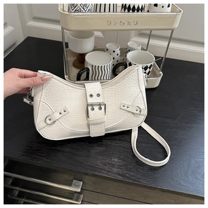 Detail of white crocodile texture underarm bag featuring a large silver metal buckle