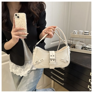 Detail of white crocodile embossed underarm bag with decorative belt buckle and silver hardware