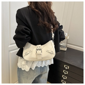 Detail view of cream-colored crocodile pattern saddle bag styled with a black blazer