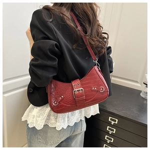 Detail of dark red crocodile-pattern baguette bag with large silver metal buckle strap