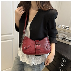 Detail of red croc-effect shoulder bag featuring a silver buckle and retro biker style