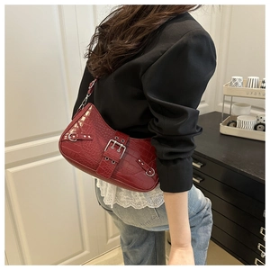 Deep red crocodile embossed baguette bag with silver buckle shown on a model's shoulder