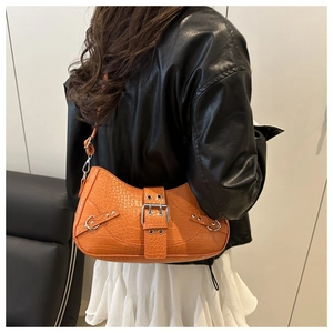 Detail of orange crocodile pattern bag with silver metal buckle and rivets on model