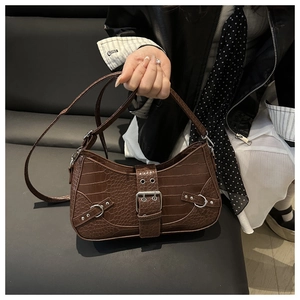 Macro detail of dark brown crocodile embossed saddle bag with silver buckle and rivets