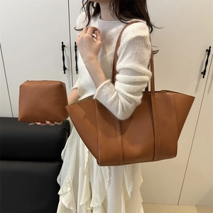Minimalist caramel brown leather tote bag with matching pouch shown in a lifestyle scene
