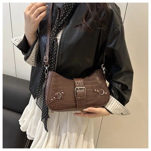 Detail of dark brown faux crocodile baguette bag with silver rivets and buckle