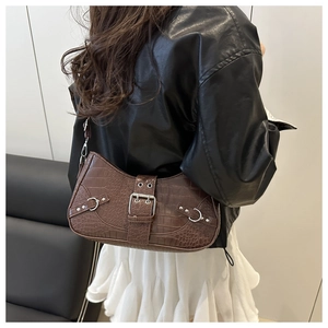 Close-up of brown crocodile texture shoulder bag with wide strap and silver buckle detail