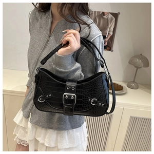 Detailed view of crocodile pattern texture and silver buckle on black underarm bag
