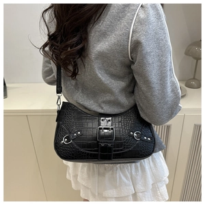 Detail of black faux leather shoulder bag featuring crocodile texture and silver metal buckle