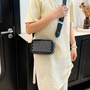 Fashionable black crossbody camera bag with silver rivets and wide strap shown on model