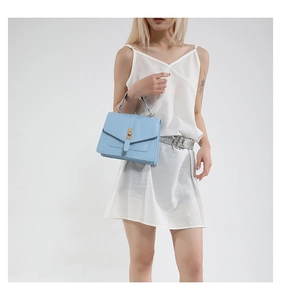 Detail of light blue crossbody bag with a metal twist lock and minimalist square design