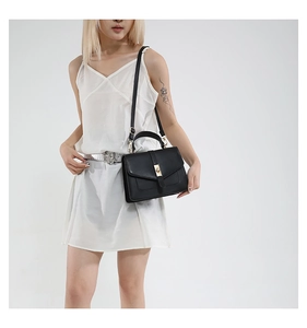 Black rectangular crossbody bag with gold buckle shown on model in studio setting