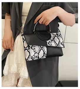 Detail of snake skin print and black leather clutch with silver metal top handle