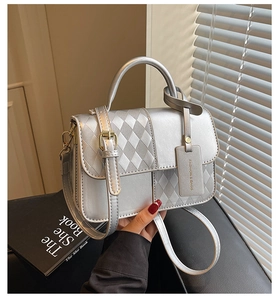 Detail of silver metallic handbag featuring quilted texture and adjustable shoulder strap