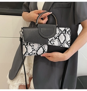 Detail of snake print texture and silver metal handle on a black and white clutch bag