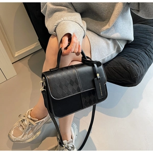 Detail of black quilted leather handbag showing the texture and fashion hangtag