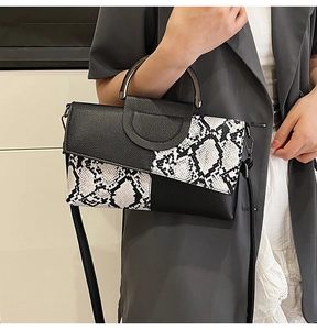 Detail of snake skin texture and black leather paneling on a modern crossbody bag
