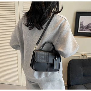 Detail of a black quilted crossbody bag showing fashion tag and matte leather texture