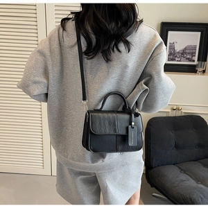 Detail of black quilted shoulder bag with fashion leather tag and detachable strap