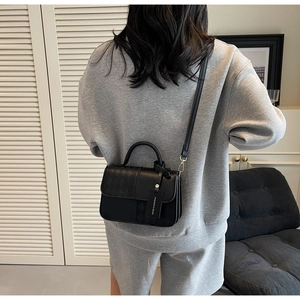 Detail of black crossbody box bag with mixed quilted and smooth faux leather texture