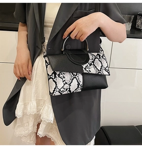 Detail of snake skin print patchwork handbag with a metallic round handle and shoulder strap