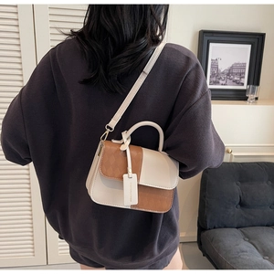 Detail of a chic cream and brown quilted crossbody bag shown on a shoulder in a room