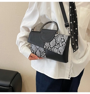Close-up of snakeskin patchwork handbag featuring metallic round handle and grainy leather texture