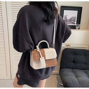 Detail view of a beige and brown quilted crossbody bag shown on a model for size and fit