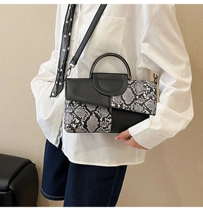 Detail of snake skin pattern handbag with metal handle and detachable strap on model