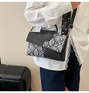 Detail of snake print textured handbag featuring silver metal hooks and detachable strap