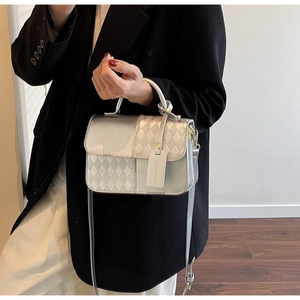 Detail of silver quilted handbag featuring sleek metallic texture and top handle