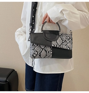 Detail of snake print clutch featuring metal ring handle and polka dot shoulder strap