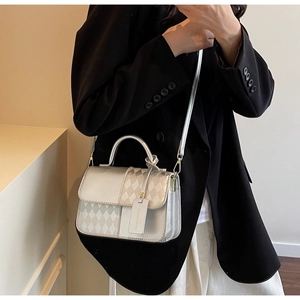 Detail of silver crossbody bag with contrast stitching and branded metal charm tag